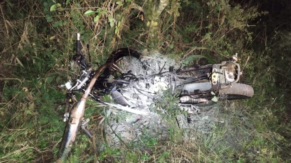 motocicleta totalmente destruída sobre vegetação