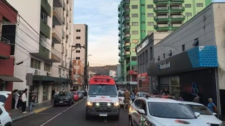 rua movimentada com prédios, carros e uma ambulância