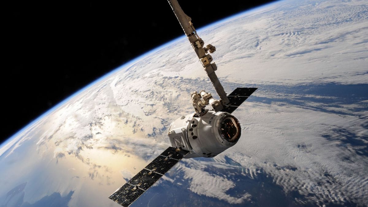 Satélite de alta tecnologia orbitando a Terra, com painéis solares abertos e a curvatura do planeta ao fundo.