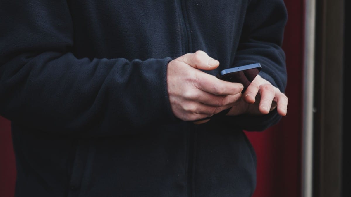 Mão de uma pessoa segurando um smartphone na rua