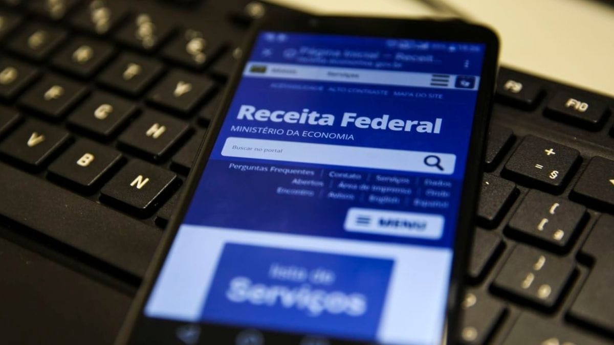 Imagem mostra em close-up um celular com a tela preenchida com a Receita Federal em cima de um teclado de computador para ilustrar matéria sobre o novo CNPJ