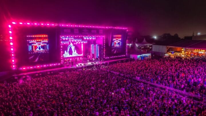 palco com luzes cor de rosa e multidão na plateia