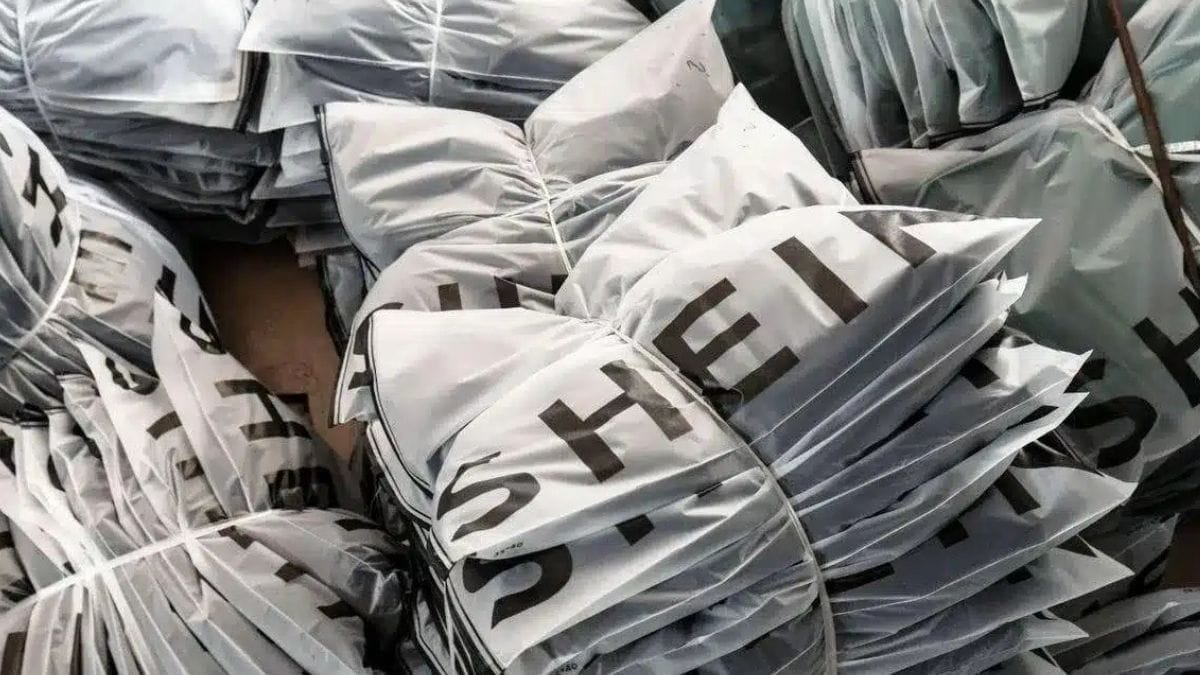 Vários pacotes plásticos de envio de roupas com a inscrição da marca Shein empilhados e amarrados, ilustrando as encomendas que circulam sem a cobrança da taxa das blusinhas.