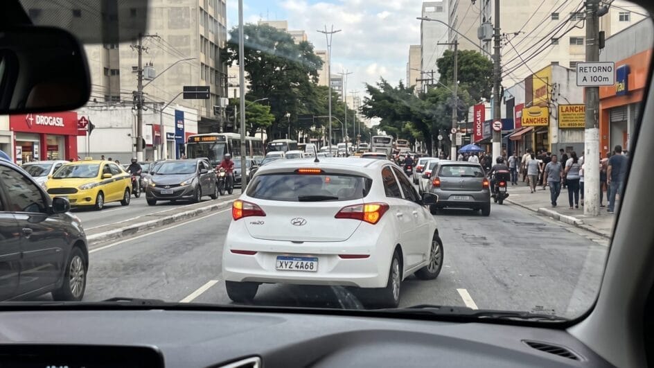 Foto mostra um carro hb20 dando seta à direita como se fosse fazer a manobra na rua em uma via movimentada de São Paulo
