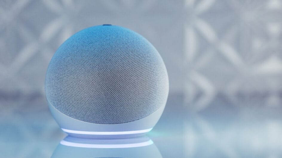 Dispositivo de som inteligente circular com um anel de luz azul brilhando no topo sobre o topo de um móvel.