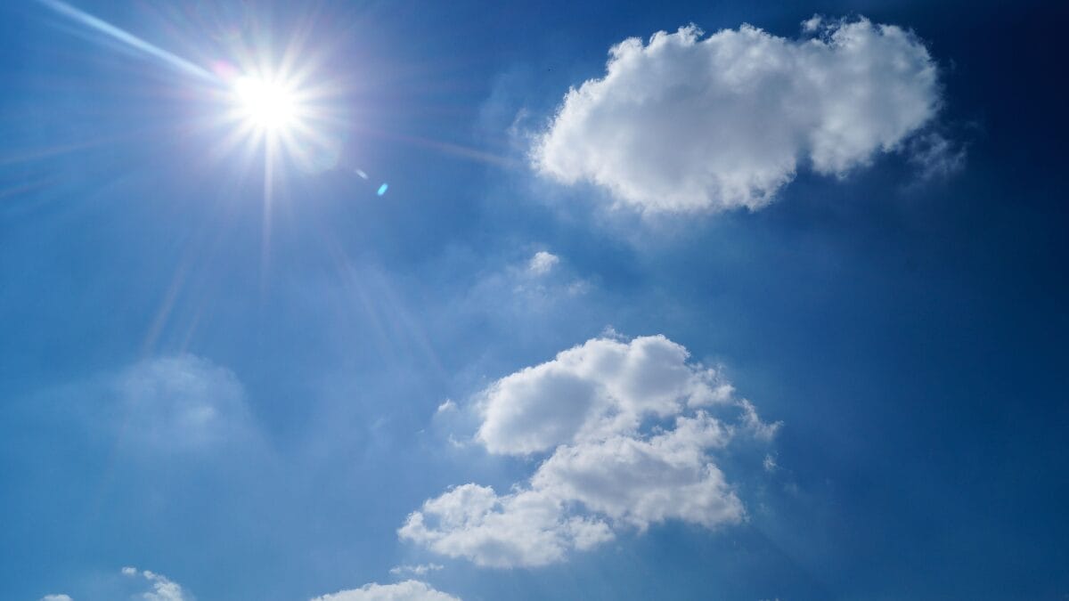 sol e nuvens em céu azul