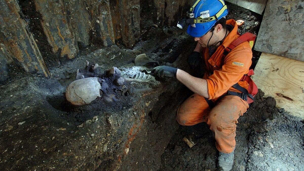 Arqueólogo escava restos humanos em uma trincheira; ossos pequenos e frágeis podem se deteriorar, se deslocar ou desaparecer durante o trabalho (Foto: crossrail/MOLA / Wikimedia Commons / Imagem Ilustrativa)