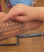 Mãe tatua teclado no antebraço para filho autista se comunicar quando o tablet fica sem bateria