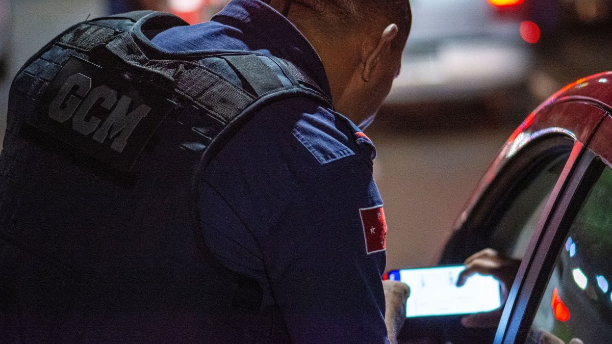 Agente de trânsito posicionando o dispositivo de teste passivo próximo à janela do motorista.