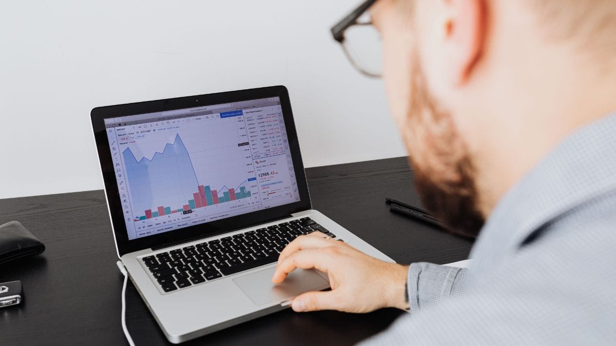 Profissional analisando gráficos corporativos em um computador no escritório.
