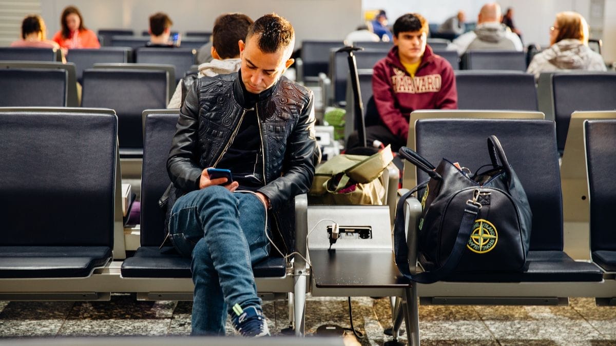 Passageiro aguarda atendimento sentado no terminal, com malas e outras bagagens ao lado