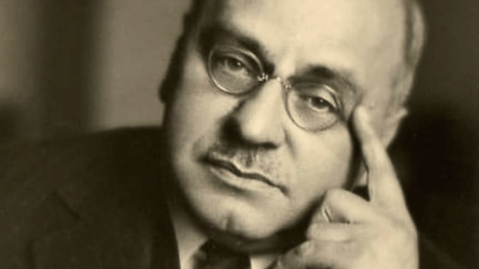 Retrato em preto e branco do psiquiatra austríaco Alfred Adler, de terno e óculos redondos