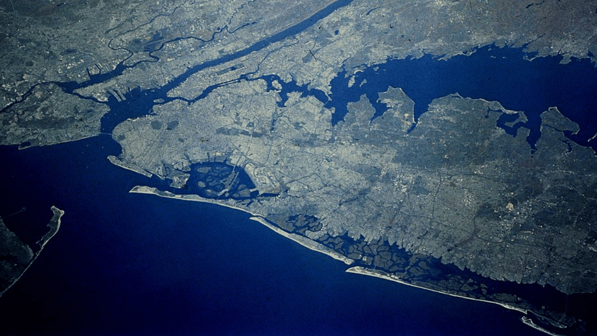 Vista orbital mostra a escala da proposta, que transformaria a entrada da baía em uma grande linha de defesa contra tempestades (Foto: NASA / Wikimedia Commons)