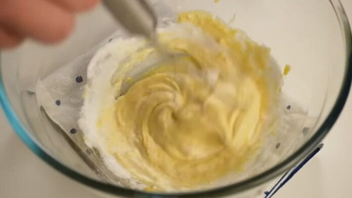 Colher misturado as claras em neve na mistura com gemas, leite e extrato de baunilha
