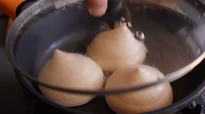 Frigideira com três panquecas sendo destampada