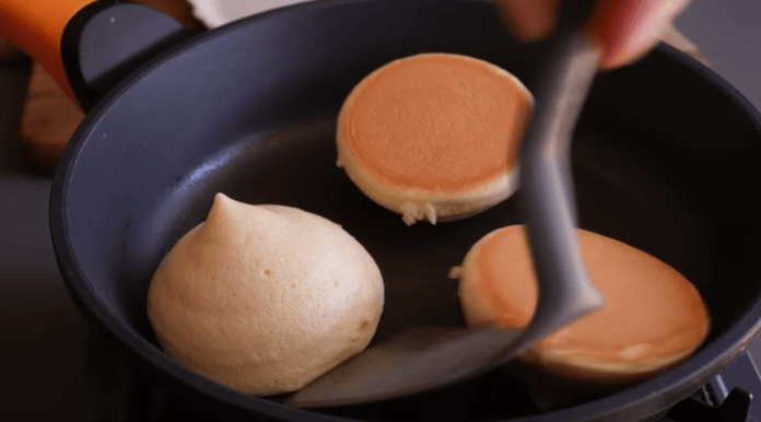 Cozinheiro virando as panquecas para dourar e assar do outro lado