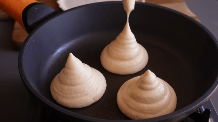 Massa de panqueca sendo despejada na frigideira em formato de coxinha