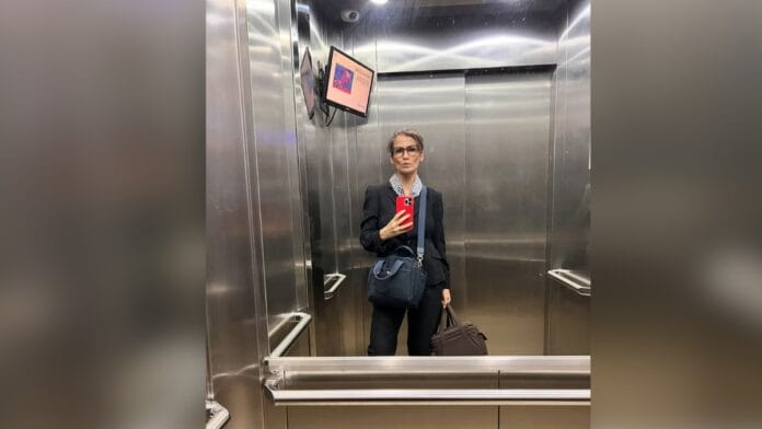 Jornalista Renata Vasconcellos, de cabelo castanho e óculos de armação escura, com blazer e calça de alfaiataria em preto