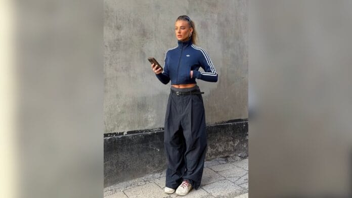 Mulher com jaqueta cropped azul, de gola lata, calça cintura baixa larga cinza escuro