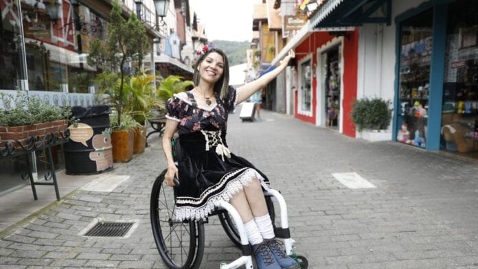 Mulher em cadeira de rodas usa traje típico alemão durante passeio em Blumenau