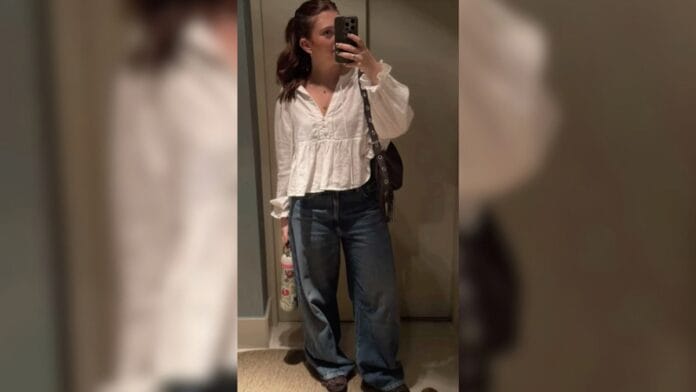 mulher com bata branca, calça jeans e bolsa preta