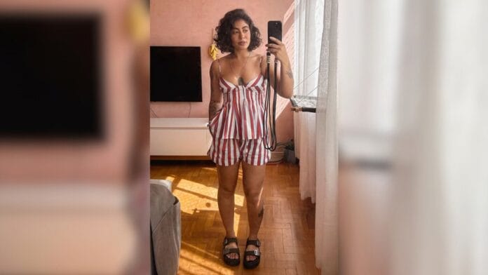 mulher com conjunto listrado de bata e short, sandália preta nos pés