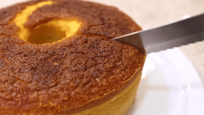 Faca corta um bolo de milho assado, mostrando a massa amarela e macia