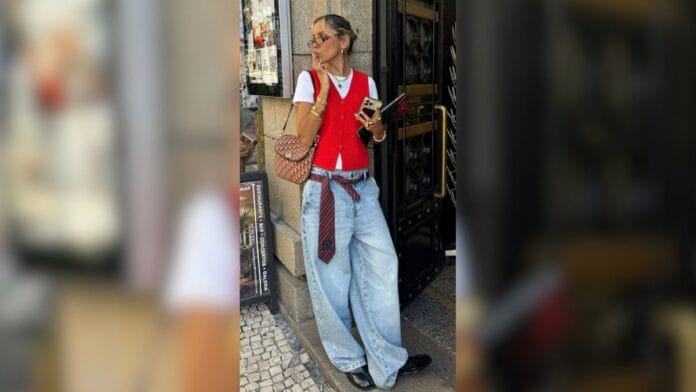 mulher com calça baggy, blusa branca e colete vermelho por cima