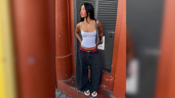 mulher com regata branca, calça baggy e cinto vermelho