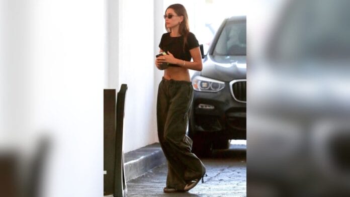 Mulher com com cropped preto e calça cintura baixa verde escuro