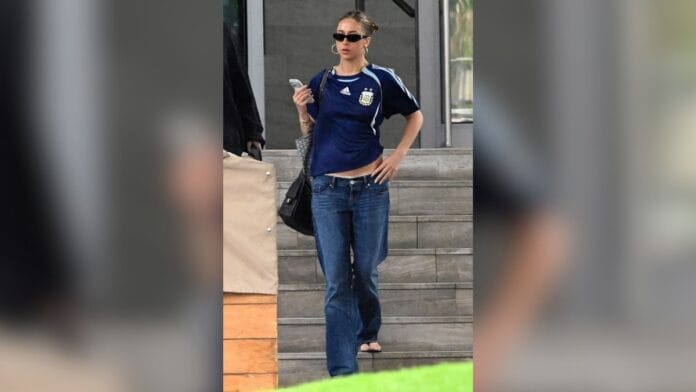 mulher com calça cintura baixa azul escuro, blusa de time azul
