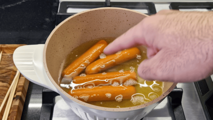Salsichas sendo fervidas em uma panela com água sobre o fogão
