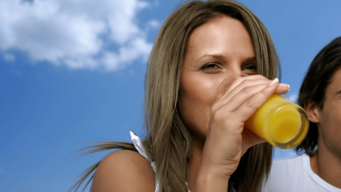 Mulher bebe um copo de suco ao ar livre