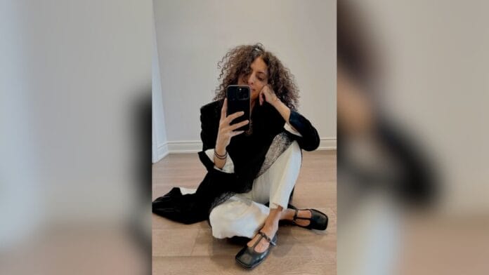 mulher com camisa social branca, blazer preto, calça larga e solta branca e t-strap preto com bico quadrado
