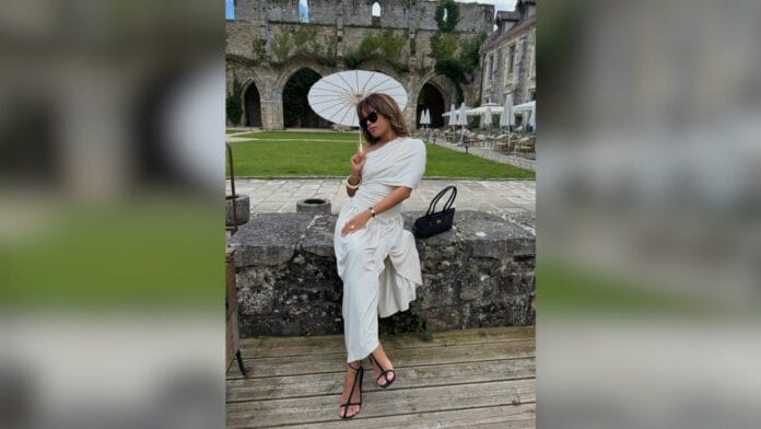 mulher com conjunto de blusa e saia brancas, com sombrinha branca e sapato t-strap no pé