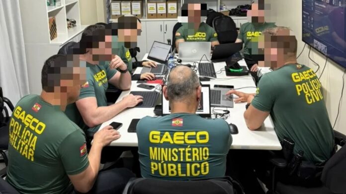 foto dos agendes sentados na mesa com computadores na frente