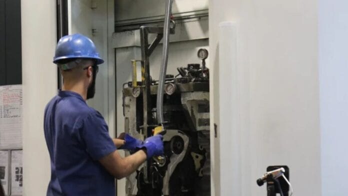 Trabalhador da Tupy de costas olhando para uma máquina