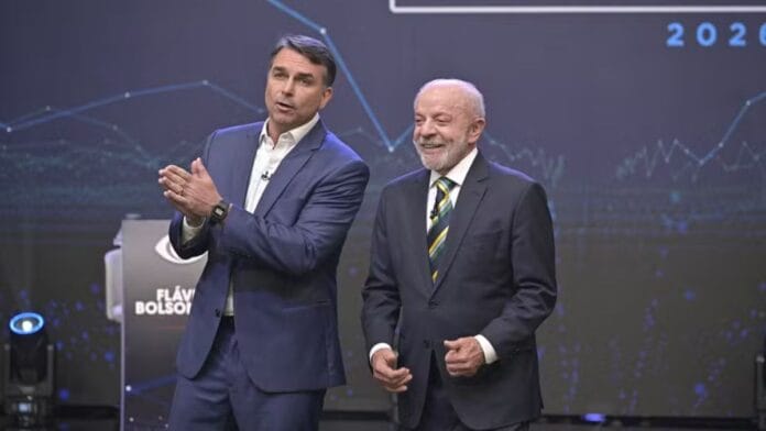 Comparação de altura Lula e Flávio Bolsonaro lado a lado no palco durante debate presidencial.
