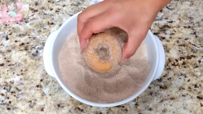 untando as rosquinhas com açúcar e canela
