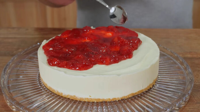 adicionando a cobertura de morango sobre a cheesecake