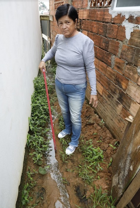 Dona Marlene mostra esgoto que invade o terreno dela e da creche