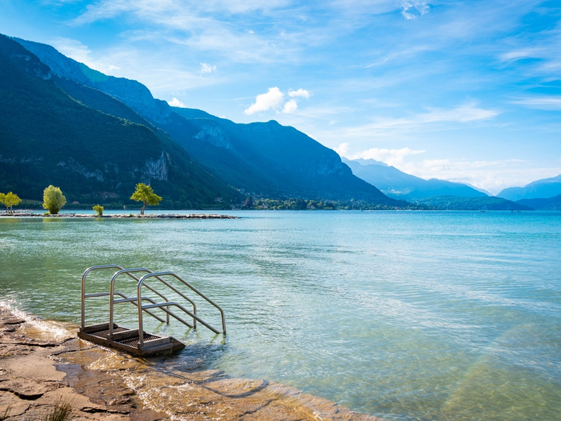 Lago de Annecy com montanha ao fundo e escada para entrar 